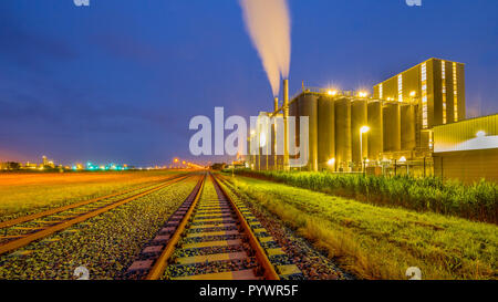 Variopinto Panorama della ferrovia in una pesante industriale area chimica con sognante mistico di luci e colori nel crepuscolo Foto Stock