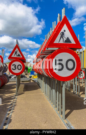 Lavori in corso il limite massimo di velocità segni tra altre righe di segni di traffico in attesa di essere ingaggiato in progetti di costruzione stradale Foto Stock