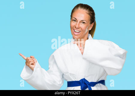 La mezza età adulto donna che indossa il karate kimono uniforme su sfondo isolato stupiti e sorridente alla fotocamera durante la presentazione con la mano e puntamento Foto Stock