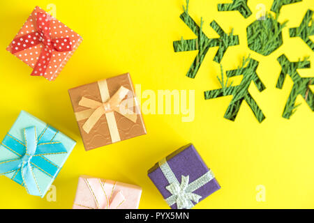 Presenta e il simbolo del fiocco di neve con albero di natale rami su sfondo giallo minimo di vacanza creativa del concetto. Foto Stock