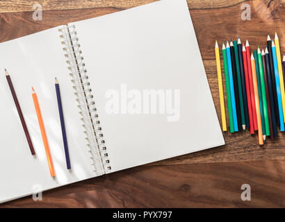 Aprire vuoti sketchbook e matite colorate su un tavolo di legno Foto Stock