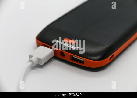 Nero/Arancio 10000mah 'Powerado' energia retro con pannello solare. Cavo USB bianco ad esso collegato. Foto Stock