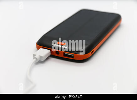 Nero/Arancio 10000mah 'Powerado' energia retro con pannello solare. Cavo USB bianco ad esso collegato. Foto Stock