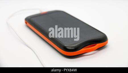 Nero/Arancio 10000mah torna con pannello solare. Cavo USB bianco ad esso collegato. Foto Stock