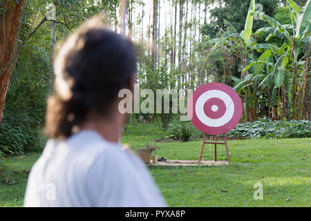 Un maschio sport archer sparare una freccia con un inchino ad un rosso bersaglio in legno Foto Stock