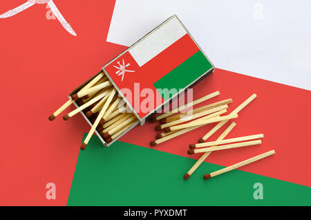 Oman flag è mostrato su un open matchbox, da cui diversi corrisponde a caduta e giace su di una bandiera di grandi dimensioni. Foto Stock