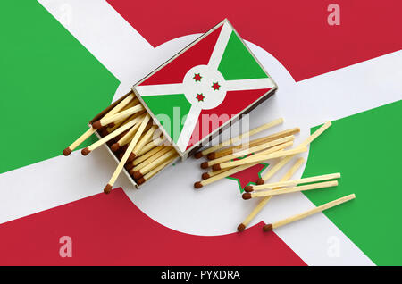 Burundi flag è mostrato su un open matchbox, da cui diversi corrisponde a caduta e giace su di una bandiera di grandi dimensioni. Foto Stock