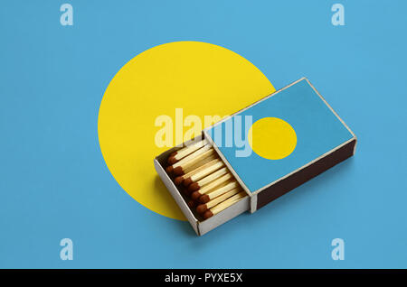 Palau flag è mostrato in un aperto la scatola di fiammiferi, il quale è riempito con corrispondenze e giace su di una bandiera di grandi dimensioni. Foto Stock