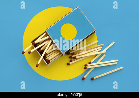 Palau flag è mostrato su un open matchbox, da cui diversi corrisponde a caduta e giace su di una bandiera di grandi dimensioni. Foto Stock