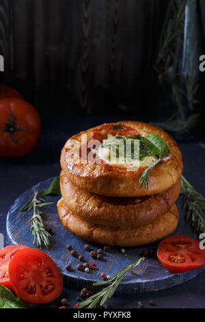 Tre in casa mini pizza con pomodori, formaggio e pancetta, lesioni e spezie su fondo azzurro copia verticale dello spazio Foto Stock