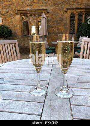 Due flauti di champagne seduta sul legno Tavolo picnic Foto Stock