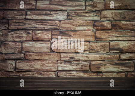 Sullo sfondo di un muro di mattoni con un tavolo di legno illuminato da luce. La vignettatura Foto Stock