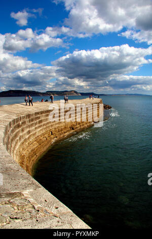 La gente camminare lungo il Cobb a Lyme Regis nel Dorset, Inghilterra Foto Stock