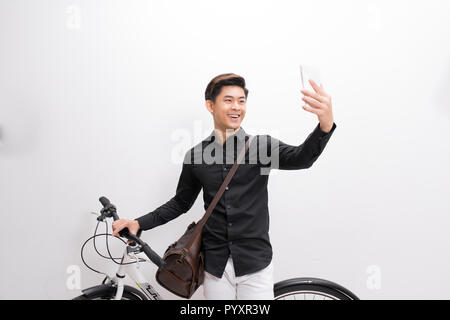 Hipster uomo prendendo un selfie . Egli è il pendolarismo, egli ha un ingranaggio fisso bike. Stile di vita, di viaggio e di concetti di sostenibilità. Foto Stock