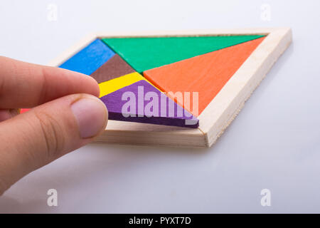 Mano che tiene un pezzo mancante di un puzzle tangram Foto Stock