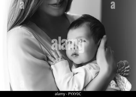 Vista parziale della donna che la porta little baby boy davanti di tende Foto Stock