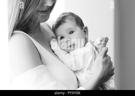 Immagine in bianco e nero di madre che trasportano little baby boy a casa Foto Stock