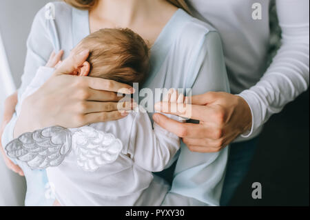 Immagine ritagliata della famiglia portando little baby boy con ali a casa Foto Stock