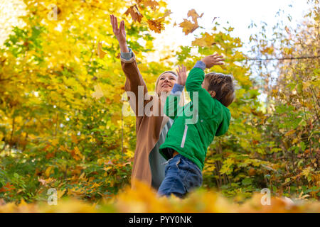 Madre e figlio abbracciando tra l'autunno all'aperto. Concetto di amicizia tra il figlio e i genitori, la famiglia felice Foto Stock