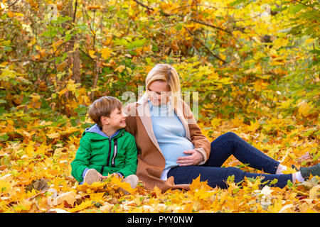 Madre e figlio abbracciando tra l'autunno all'aperto. Concetto di amicizia tra il figlio e i genitori, la famiglia felice Foto Stock