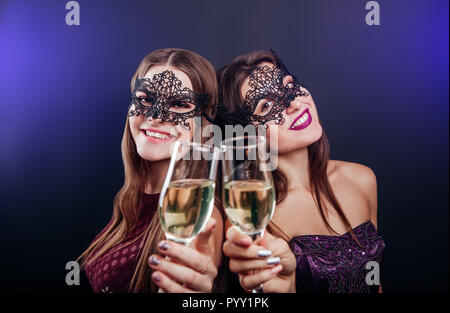 Le ragazze per celebrare il capodanno bevendo champagne su masquerade party nel club Foto Stock