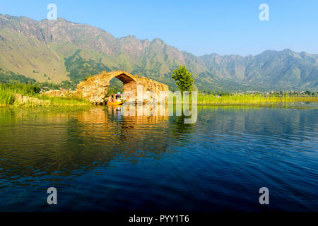 La rovina di Mughal Bridge, situato vicino al Giardino di Nishat in Dal lago, viene passato da una shikara Foto Stock