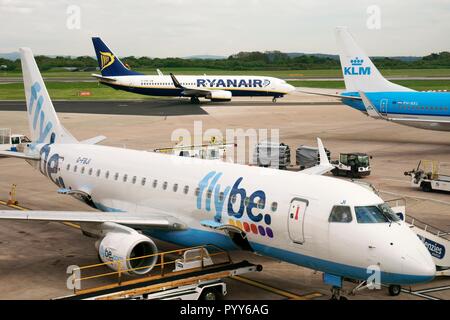Flybe, Ryanair e KLM aereo passeggeri aerei jet aereo sulla pista grembiule visto da cancelli d'imbarco di Manchester Airport Terminal, Inghilterra Foto Stock