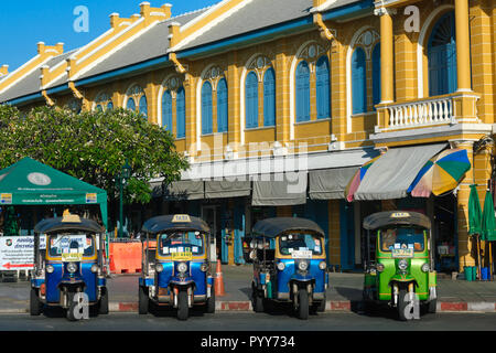 Tre ruote di taxi, cosiddetta di tuk-tuks, a fronte di un edificio di stile coloniale in uno di Bangkok aree turistiche, Thailandia, in attesa per i passeggeri Foto Stock