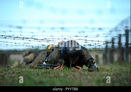 Su una formazione militare di massa, esercizi: soldato ucraino di strisciare sotto fili spinati. Ottobre 18, 2018. Novo-Petrivtsi, Ucraina Foto Stock