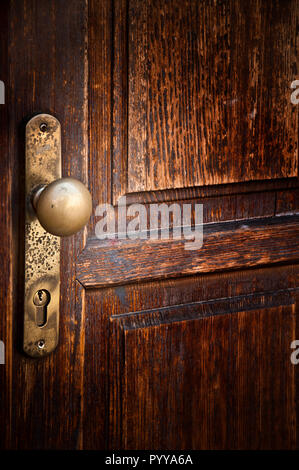 La manopola dello sportello e la serratura di una vecchia porta di legno Foto Stock