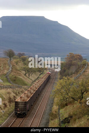 Diesel-elettrico loco alaggio rastrello di carri vuoti a stabilirsi a Carlisle linea ferroviaria tra Blea Moor tunnel e la casella segnale, Ingleborough in distanza Foto Stock