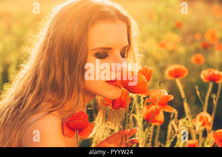 Bella ragazza nel campo sniffing fiore di papavero Foto Stock