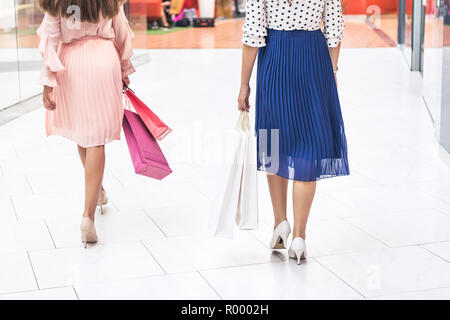 Ritagliato colpo di ragazze eleganti holding di sacchetti di carta e passeggiate nel centro commerciale per lo shopping Foto Stock