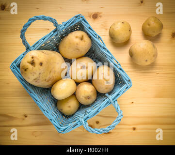 Patate fresche in legno cesto vintage sulla vecchia tabella come sfondo. Vista dall'alto. Foto Stock