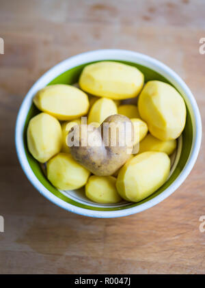 Sbucciate le patate in una ciotola, uno di patate con la buccia a forma di cuore Foto Stock