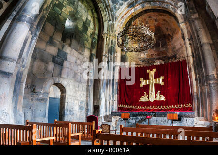 HAGHPAT, Armenia - MARZO 25, 2016: all'interno di un monastero di Haghpat - famoso in Armenia. Le righe con posti a sedere in legno di fronte a un altare. Un lampadario Foto Stock