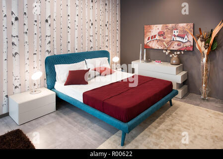 Camera da letto design con vintage letto blu sulle gambe e betulle naturali decorate parete Foto Stock