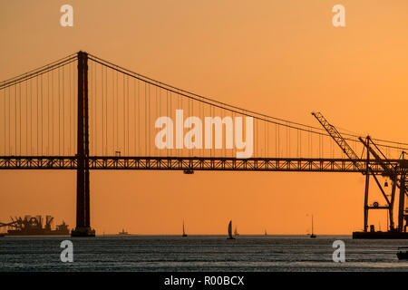 Atmosfera serale sul fiume Tago (Rio Tejo) con barca a vela e il Ponte 25 de Abril ponte di sospensione, Lisbona, Portogallo. Foto Stock