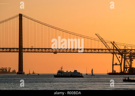 Atmosfera serale sul fiume Tago (Rio Tejo) con il traghetto e il Ponte 25 de Abril ponte di sospensione, Lisbona, Portogallo. Foto Stock