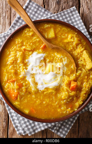 Deliziosi Mulligatawny spessa zuppa di lenticchie rosse, riso e spezie close-up in una ciotola sul tavolo. Verticale in alto vista da sopra Foto Stock