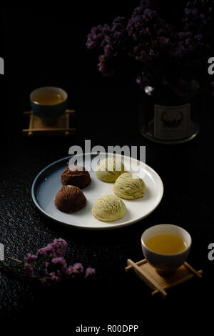Gelato artigianale Gelato Cookie servire con piastra bianca, dark style, intorno con tè, fiori, vase, cup Foto Stock