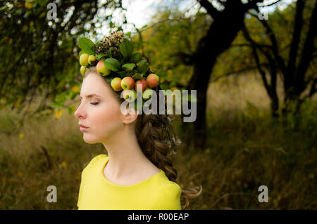 Ritratto di giovane donna in giardino di apple con la corona sulla testa e gli occhi chiusi, vista laterale Foto Stock