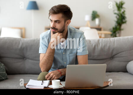 Uomo seduto sul divano pensando a casa Foto Stock