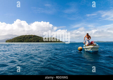 Local micronesiano uomo in una barca da pesca tira una boa al di fuori dell'acqua vicino Nan Madol, Pohnpei Island, Stati Federati di Micronesia. Foto Stock