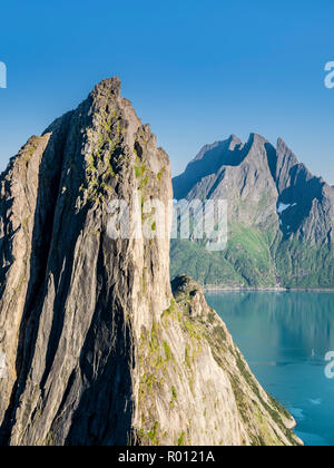 Mountain Segla visto dalla montagna Hesten, ripida scogliera, picco Breidtinden nel retro, piccola imbarcazione a vela sulla calma vedere, isola Senja, Troms, Norvegia Foto Stock