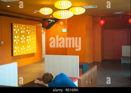 Repubblica di Singapore, uomo dorme in un centro commerciale per lo shopping Foto Stock