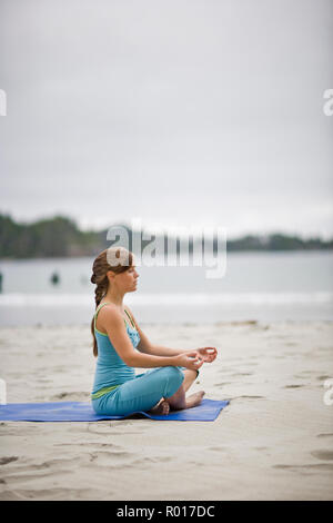 Giovane donna adulta meditando mentre fare yoga su un portico. Foto Stock