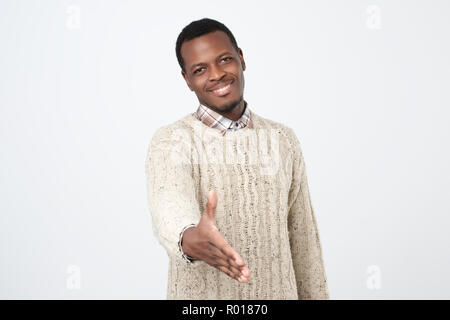 Bel giovane africano in caldi sweatergiving la sua mano per lo scuotimento Foto Stock
