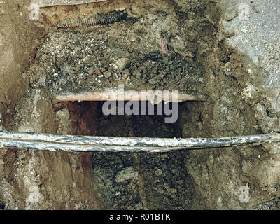 Costruzione di crossection della conduttura di acqua e linee elettriche o cavi per telecomunicazioni costruzione di collegamento alla rete ottica. Scavo e ma Foto Stock