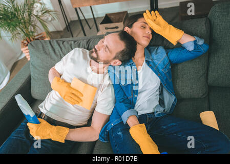 Pulire l uomo, mentre la moglie giacente con notebook sul divano di casa  Foto stock - Alamy